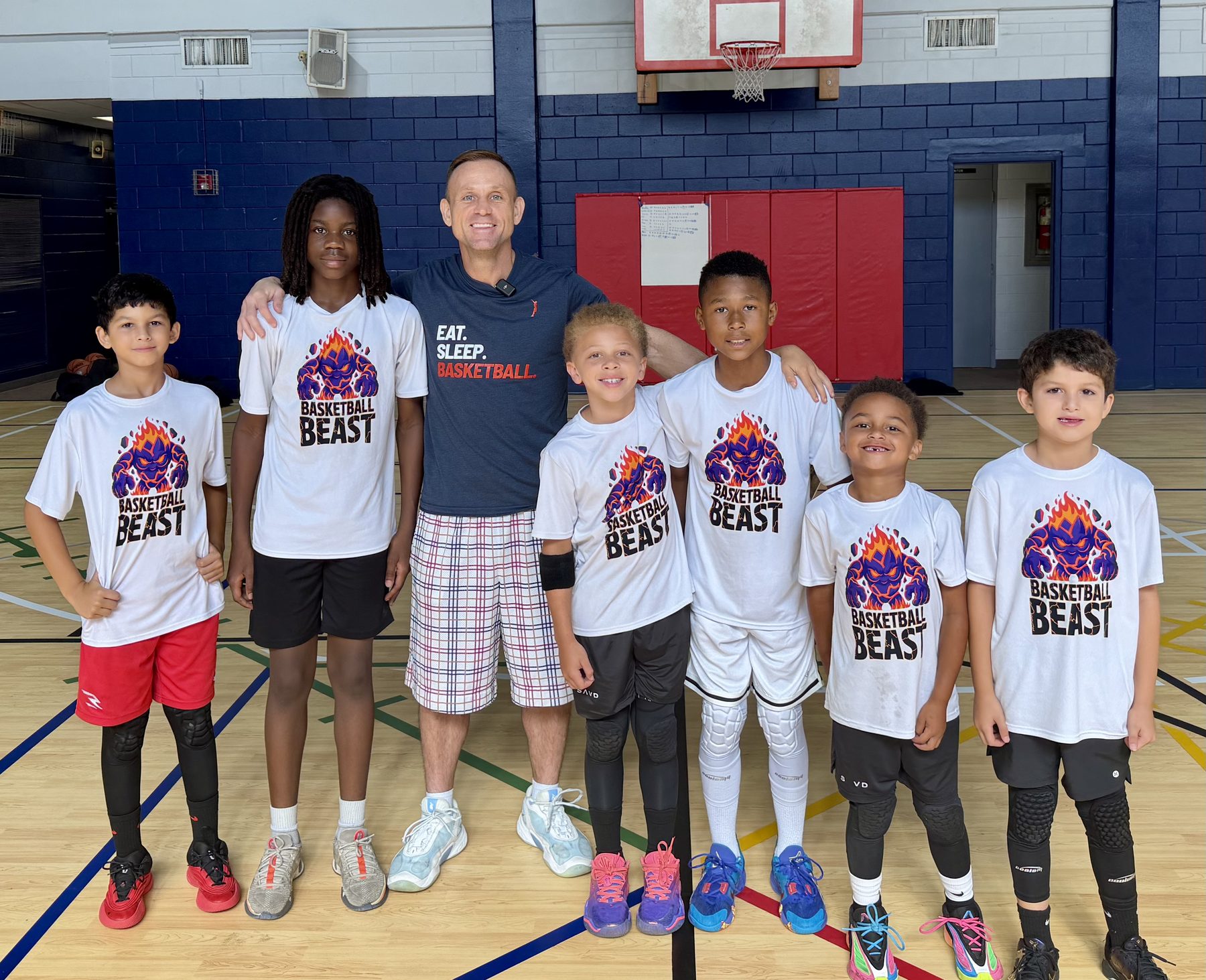 Coach Teddy with a group of TDBA campers on the court at the Activities Building